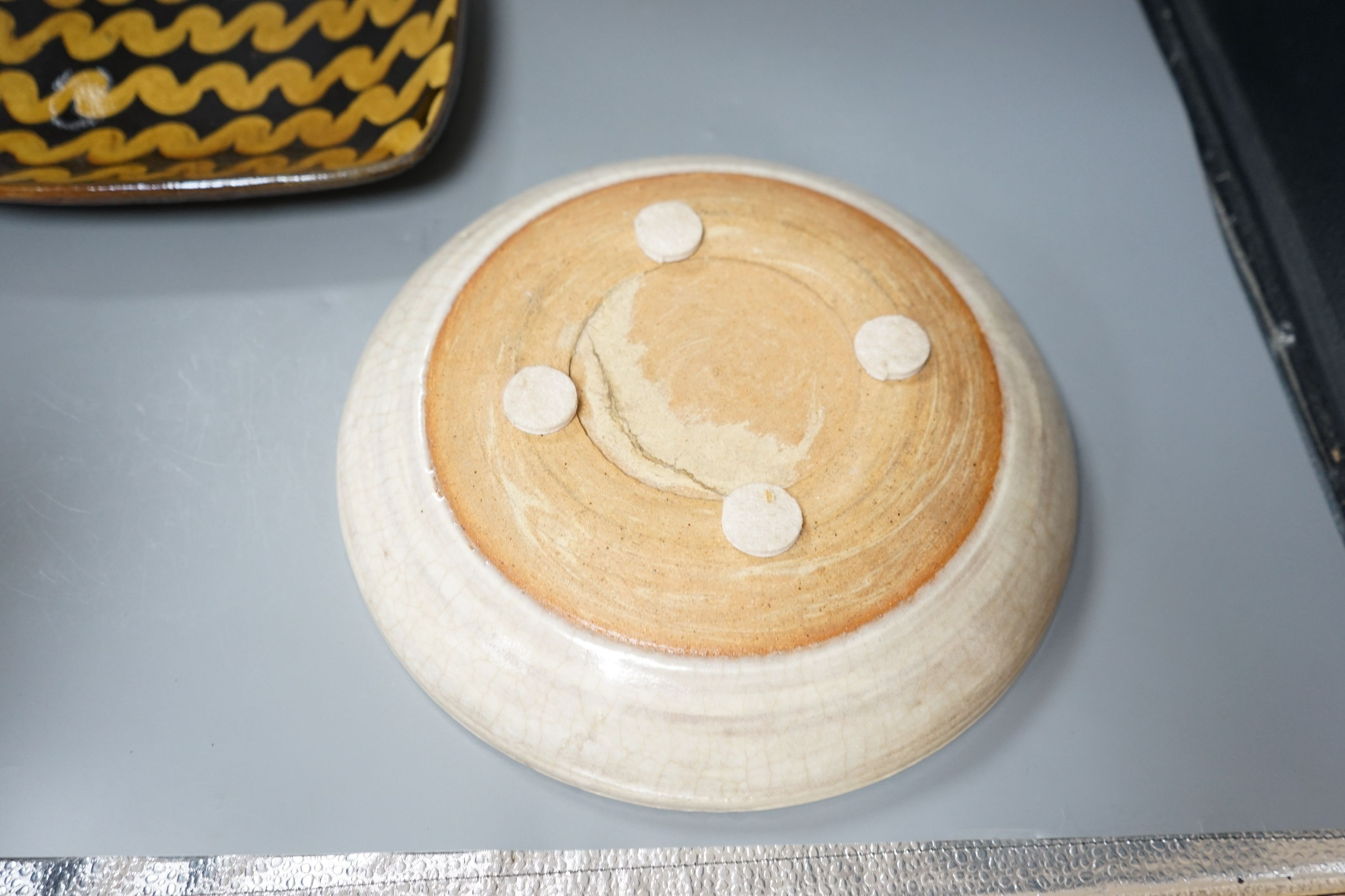 British studio pottery; Doug Fitch (b.1964), a moulded square platter with brown and yellow slip trailed decoration, 27cm wide, together with a Peter Clough (b.1944) crackle glaze dish, 29cm diameter, (2)